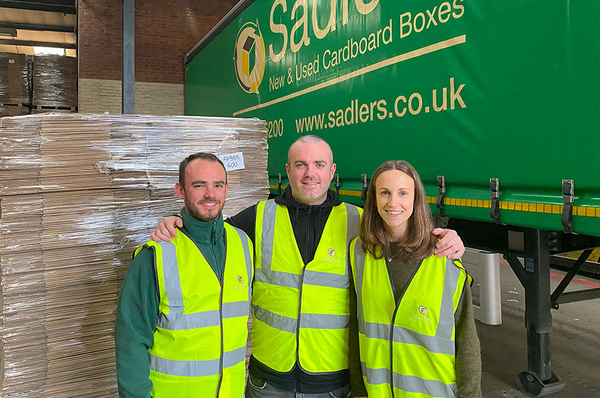 Jordan, Gavin and Lauren Sadler standing next to boxes in warehouse