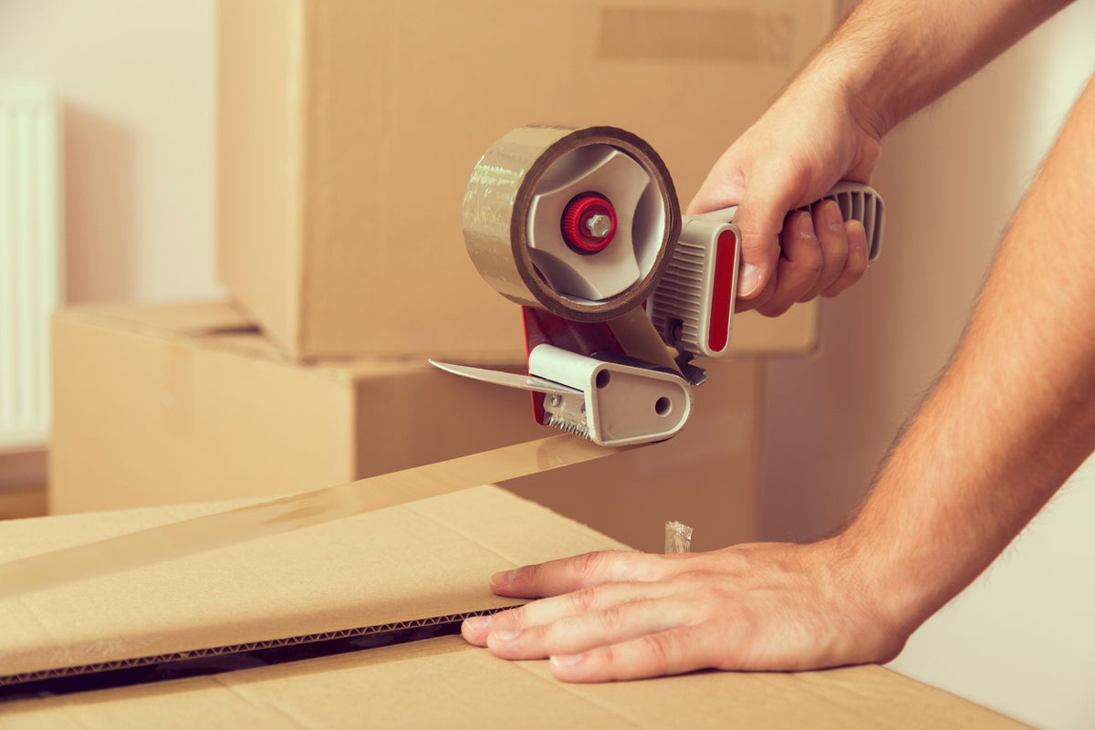 taping up a cardboard box using a tape dispenser